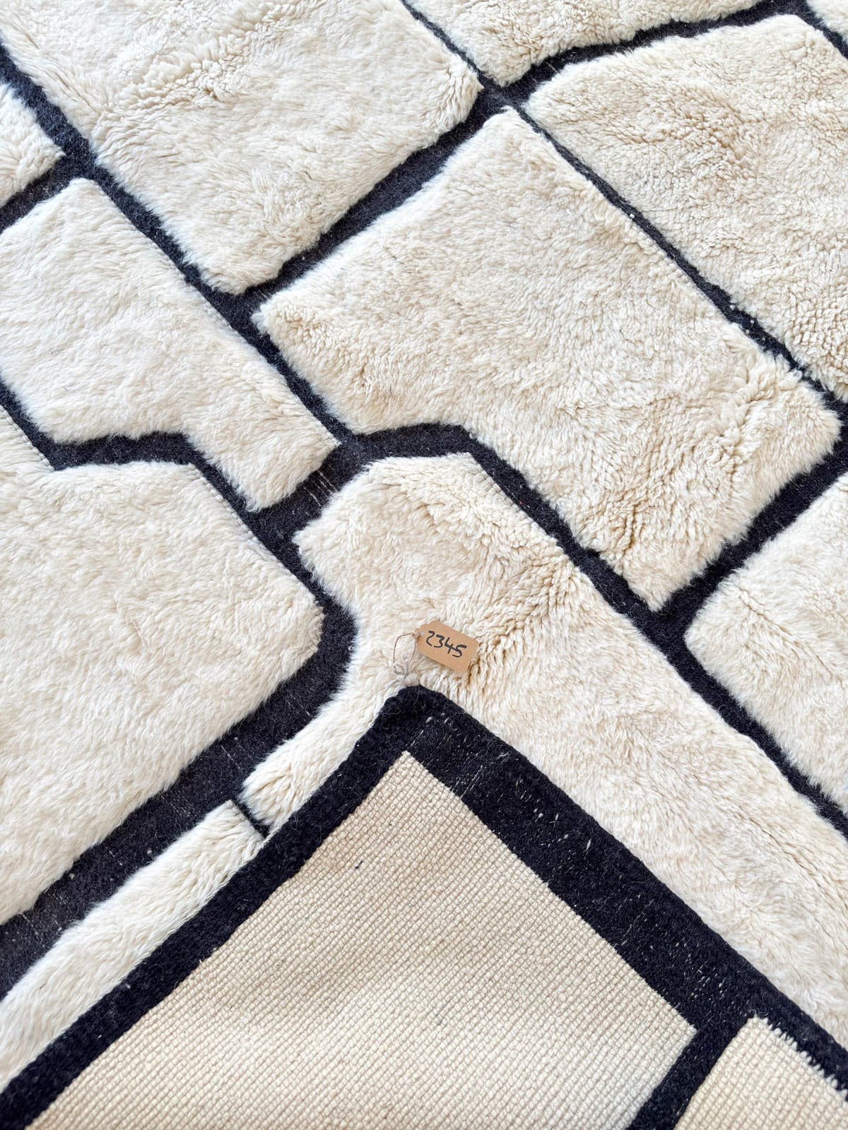 Esquina doblada de una alfombra M’rirt Tamazi: reverso tejido, lana y flecos