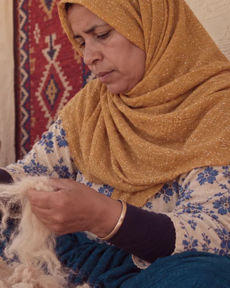 A craftswoman cards natural sheep’s wool by hand