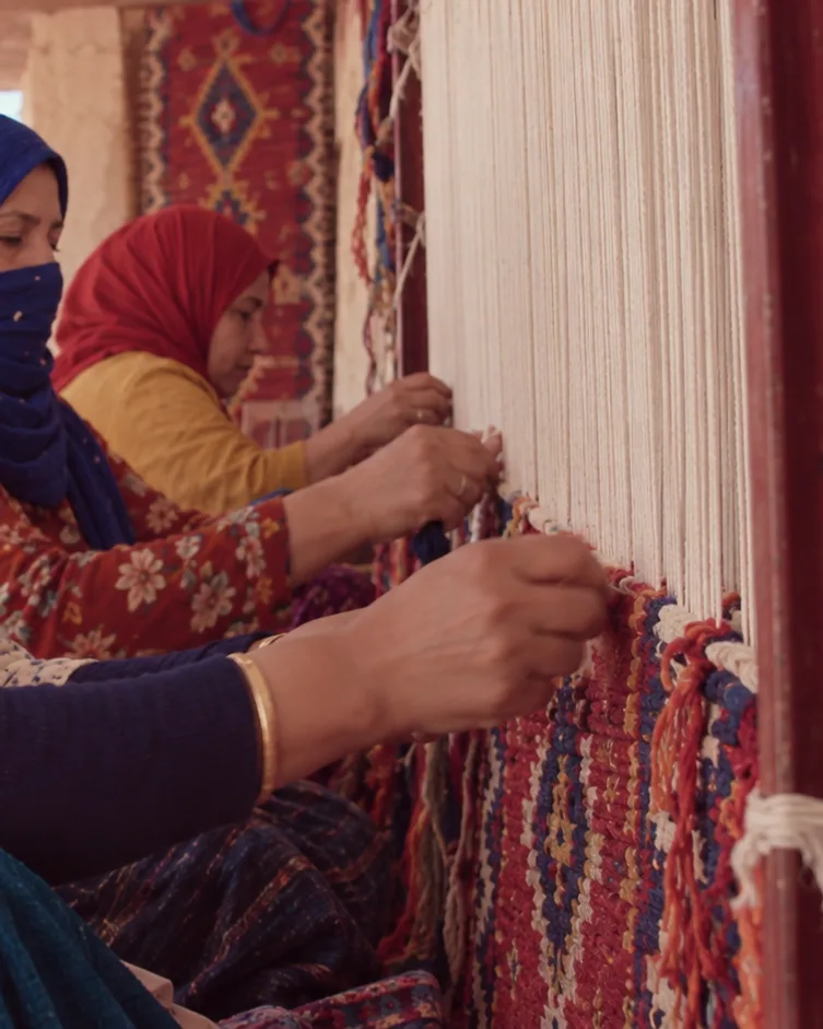 Weavers’ hands knotting wool on a traditional loom